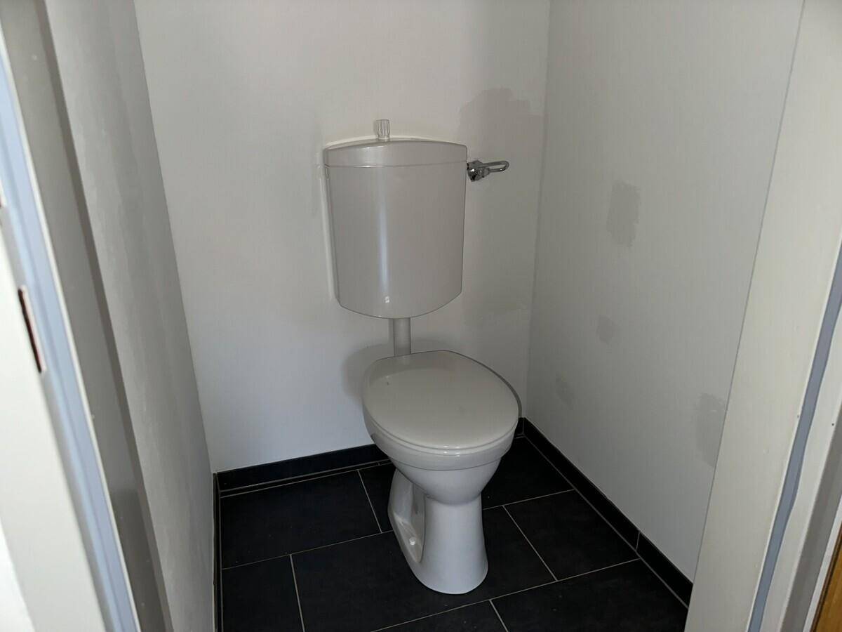 Kleines Gäste-WC mit Toilette und dunklen Bodenfliesen.