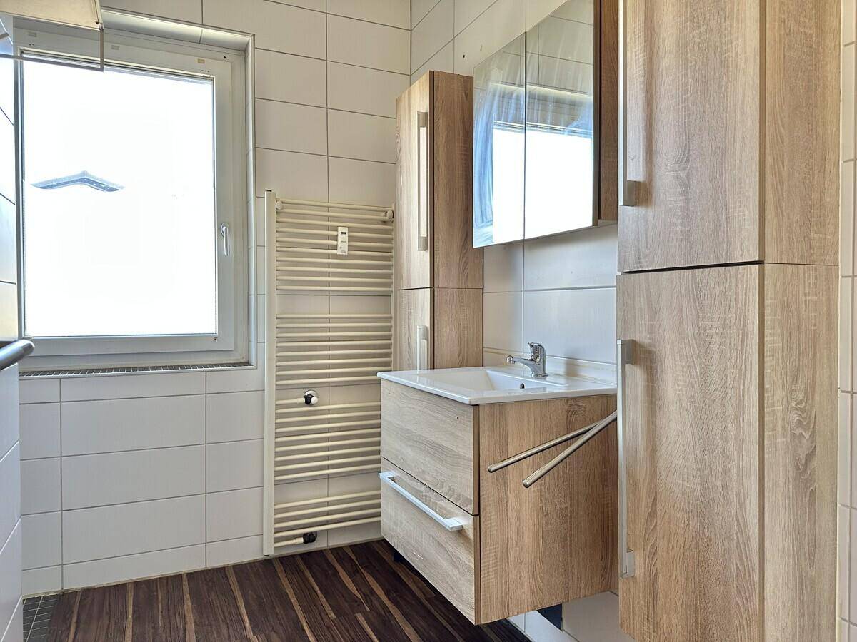 Modernes Badezimmer mit Fenster, beheiztem Handtuchhalter und Holzwaschtisch.