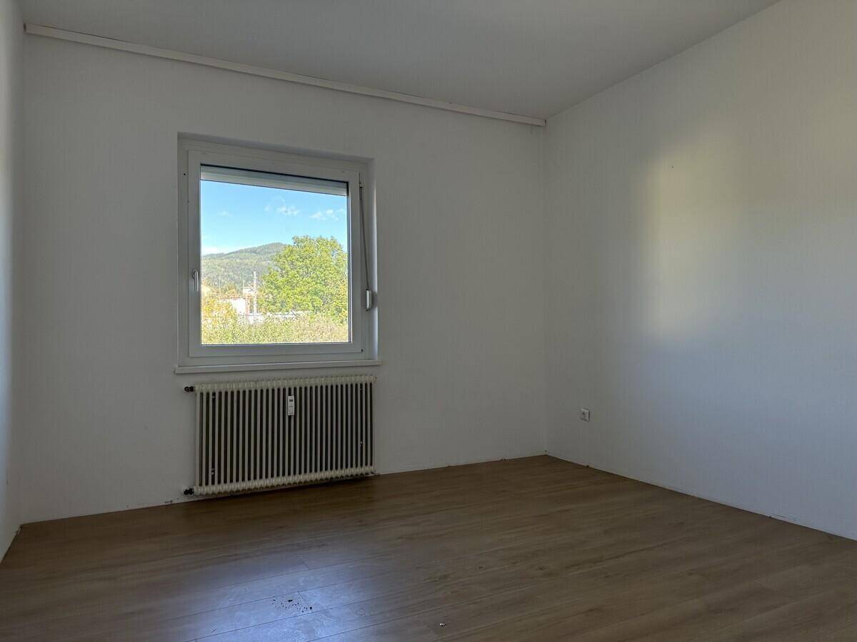 Ruhiges Schlafzimmer mit Laminatboden und Fenster mit Blick auf die Umgebung.