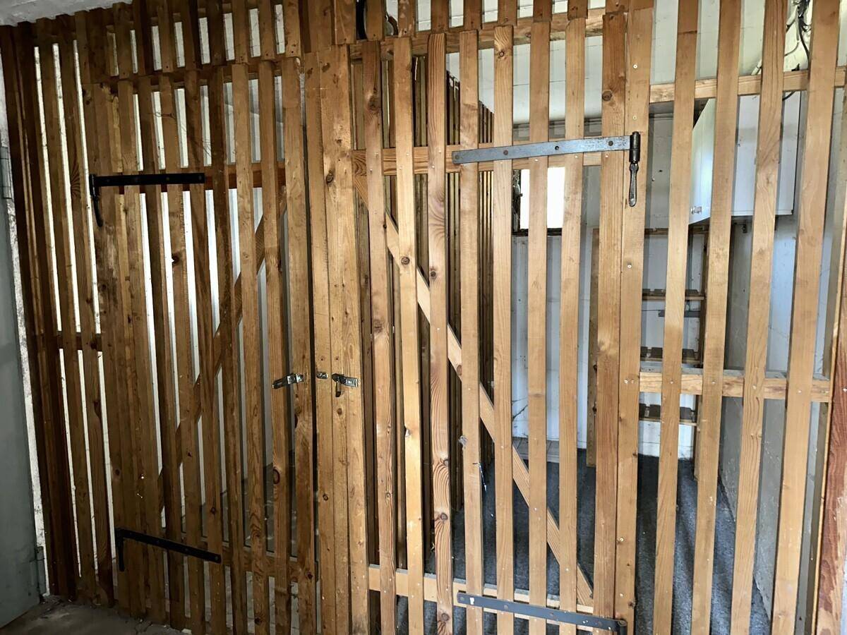 Abstellraum mit Holzlattenwänden und Stauraum für verschiedene Gegenstände.