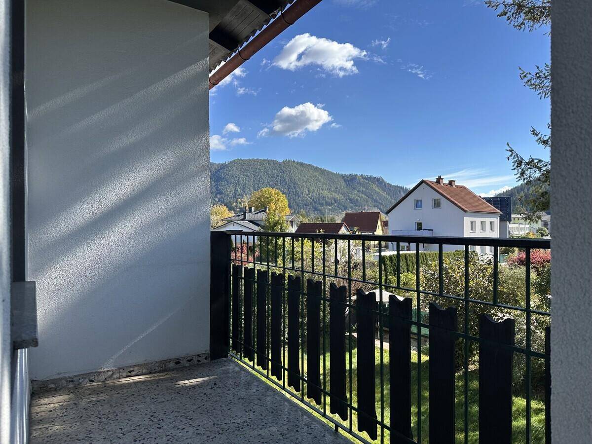 Balkon mit Metallgeländer und weitem Blick auf die Berge und umliegende Häuser.