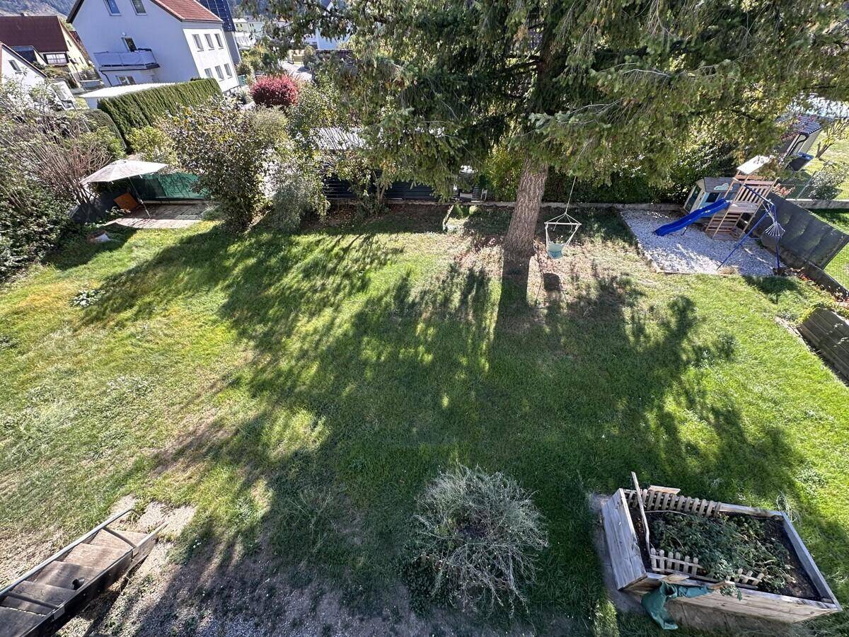 Großer grüner Garten mit Rasenfläche, Bäumen und einem kleinen Spielbereich.