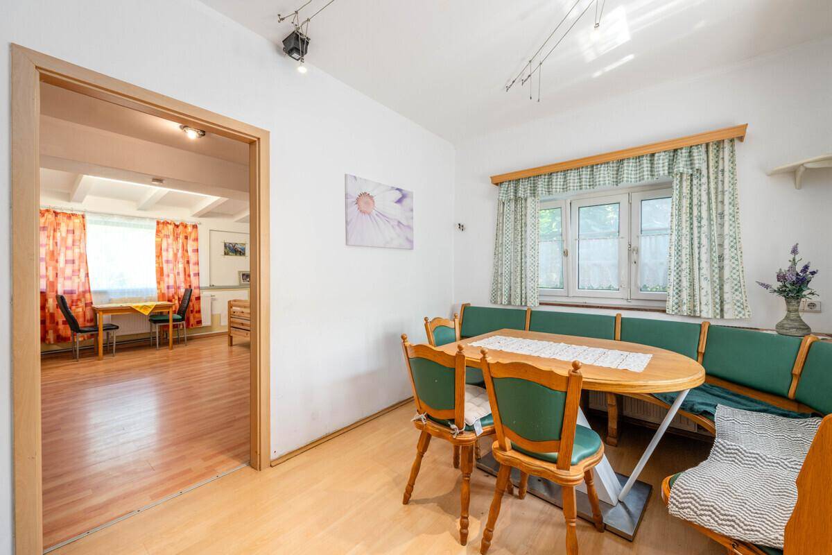 Gemütlicher Essbereich mit Eckbank und Holztisch, angrenzend an einen weiteren Raum, traditionell eingerichtet.