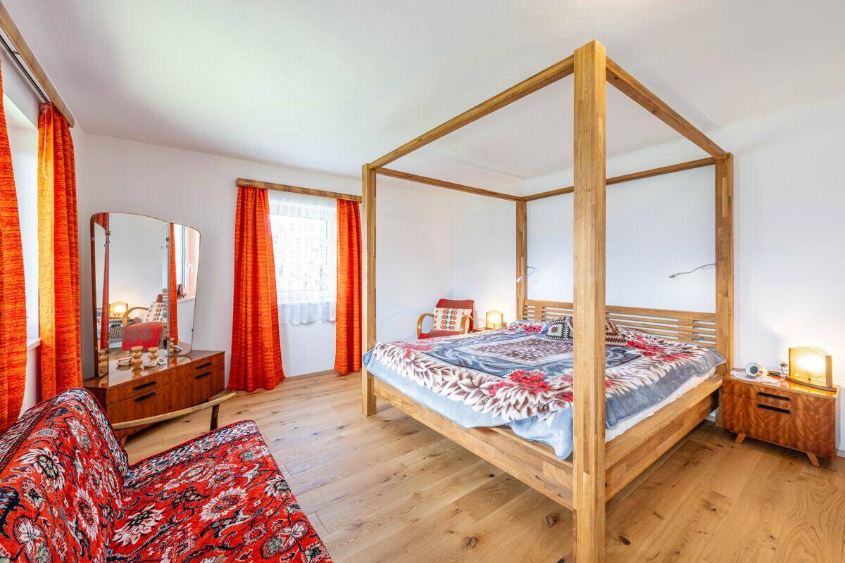 Gemütliches Schlafzimmer mit Himmelbett aus Holz, Holzboden und farbenfrohen Textilien.
