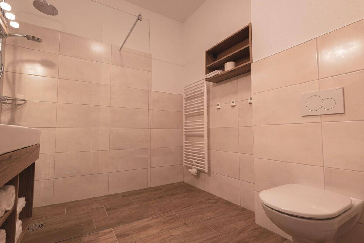Modernes Badezimmer mit ebenerdiger Dusche, Wand-WC und beheiztem Handtuchhalter.