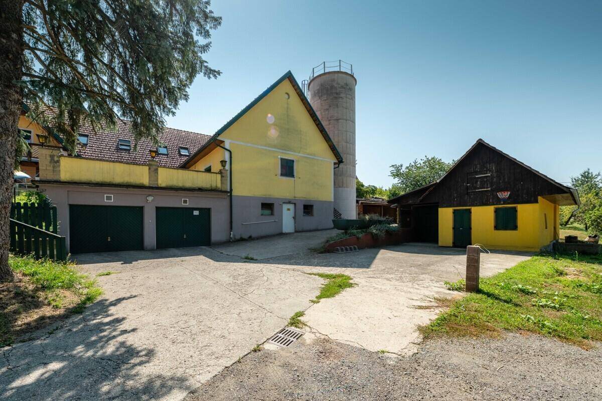 Außenansicht des Anwesens mit Parkflächen, gelben Gebäuden und einem markanten Silo.