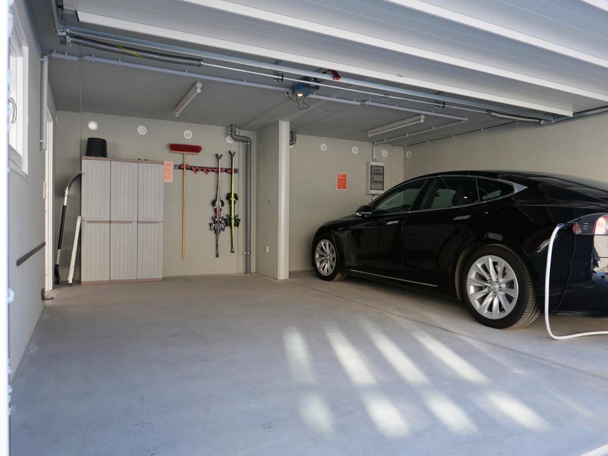Geräumige Garage mit einem Elektrofahrzeug an der Ladestation und Stauraum für Sportgeräte.