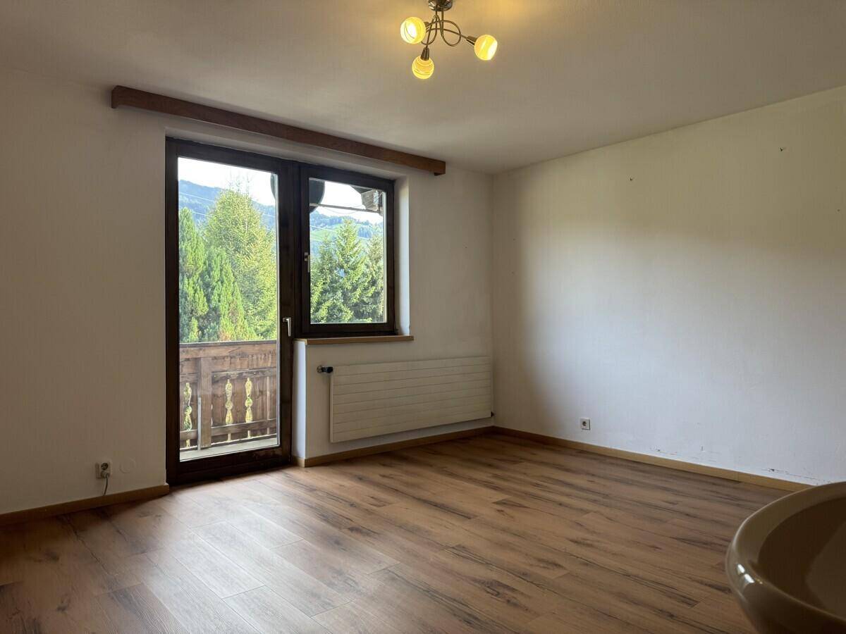 Helles Zimmer mit Laminatboden und Zugang zu einem Balkon mit Bergblick.