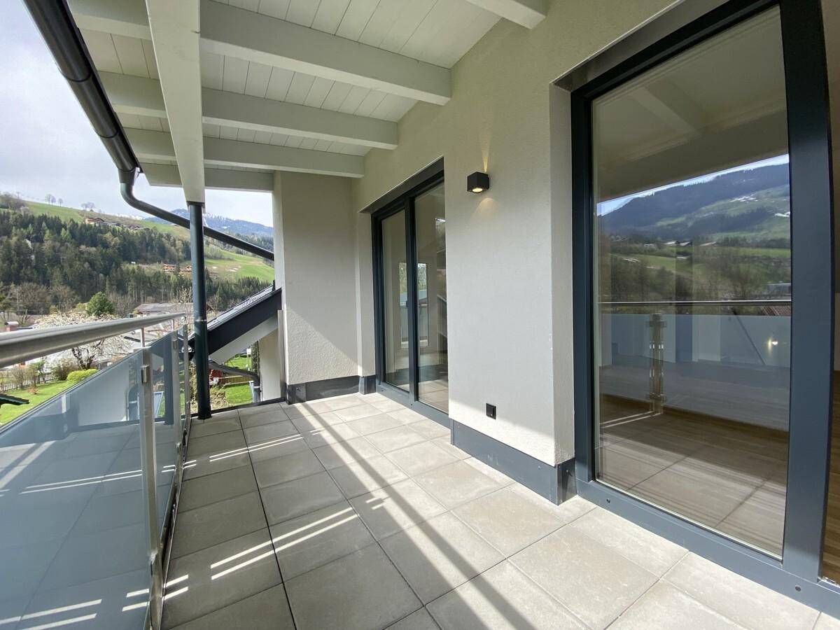 Moderner Balkon mit großen Schiebetüren und Panoramablick auf die Natur.