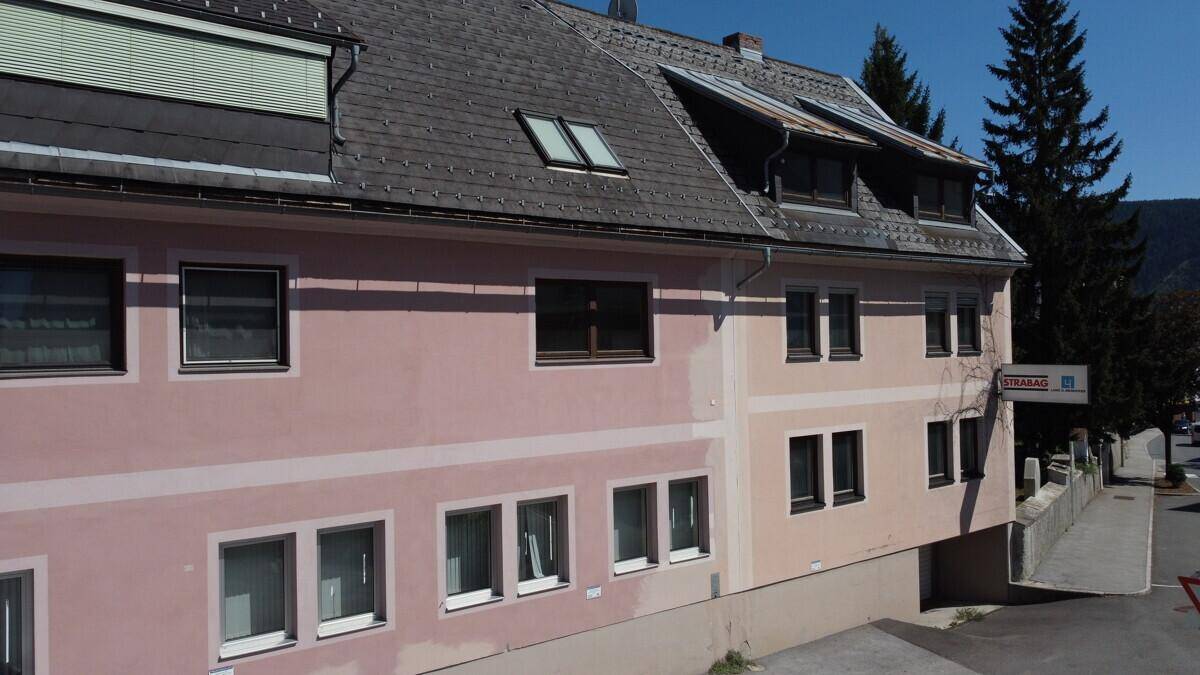 Gebäudeansicht mit rosa Fassade, Dachfenstern und Blick auf die umliegende Landschaft.