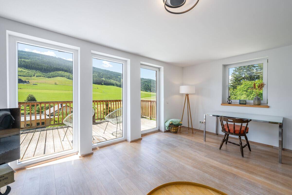 Heller Arbeitsbereich im Wohnzimmer mit großen Fenstern und direktem Zugang zum Balkon.