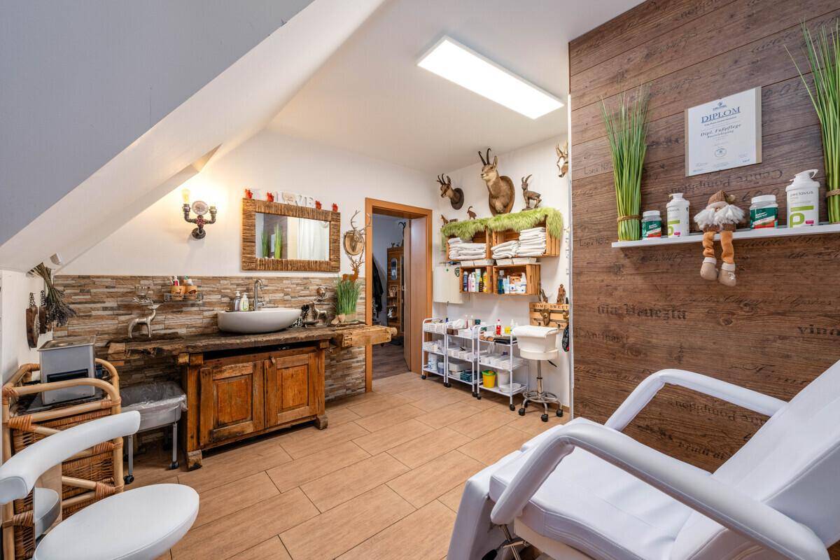Behandlungsraum mit rustikalem Waschtisch, Fliesenboden und Regalen für Wellnessprodukte.