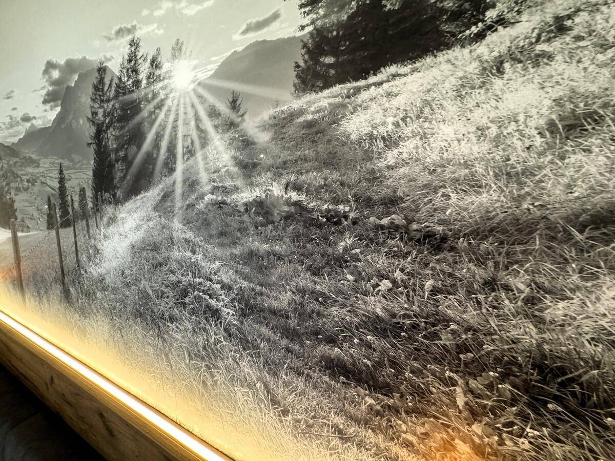 Nahaufnahme des beleuchteten Wandbildes mit sonniger Berglandschaft im Schlafzimmer.