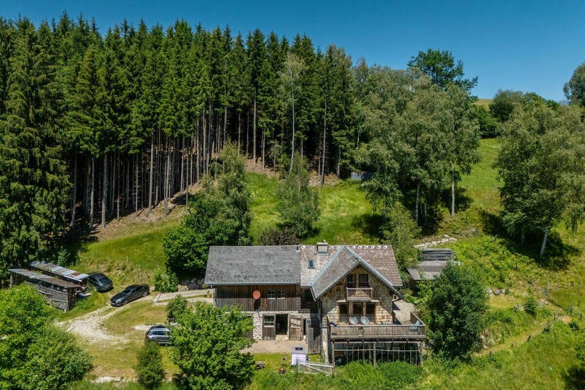 Das Chalet mit seiner Holzfassade und Terrasse fügt sich harmonisch in die bewaldete Hügellandschaft ein.