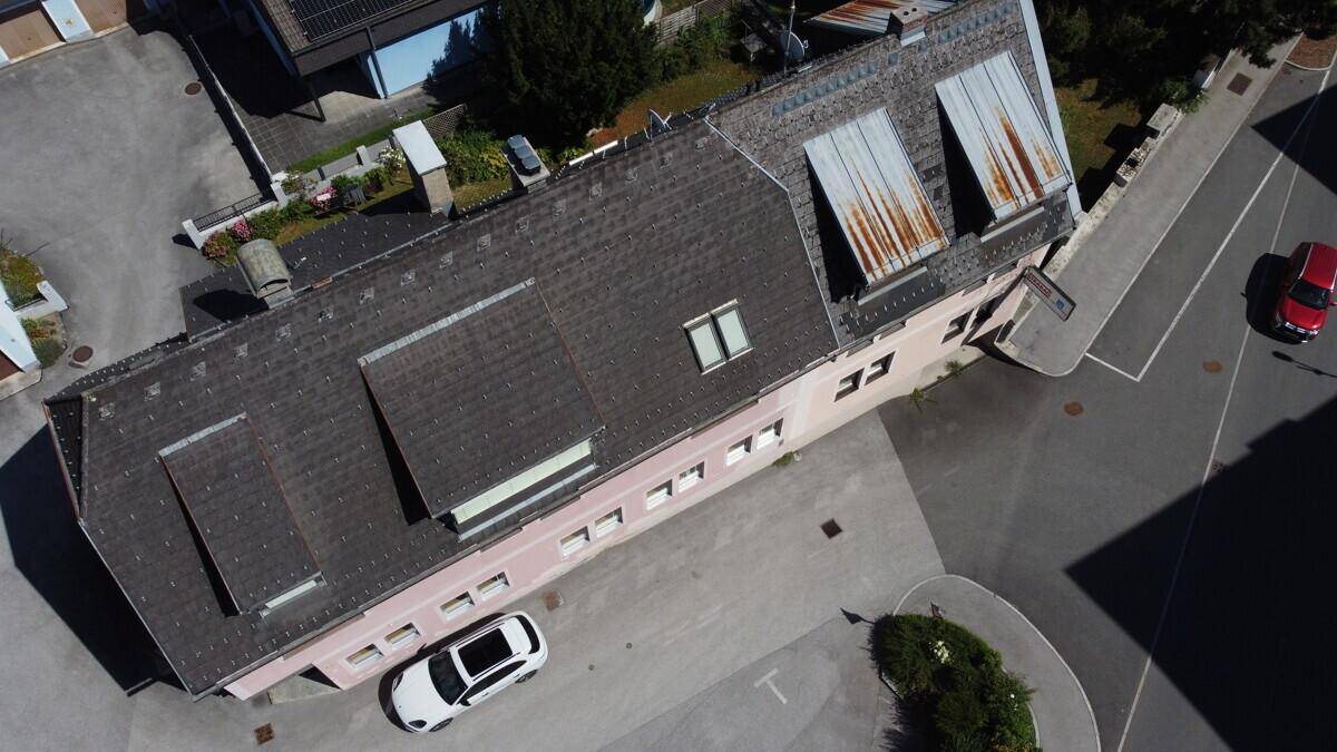 Luftaufnahme des Gebäudes mit Dach, Parkplatz und umliegenden Straßen.