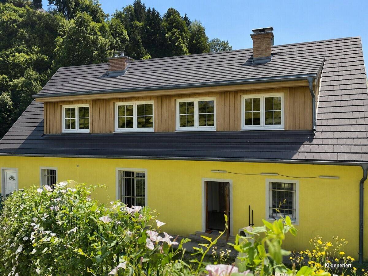 Gelbes Haus mit Satteldach, Holzverkleidung und grüner Umgebung unter blauem Himmel.