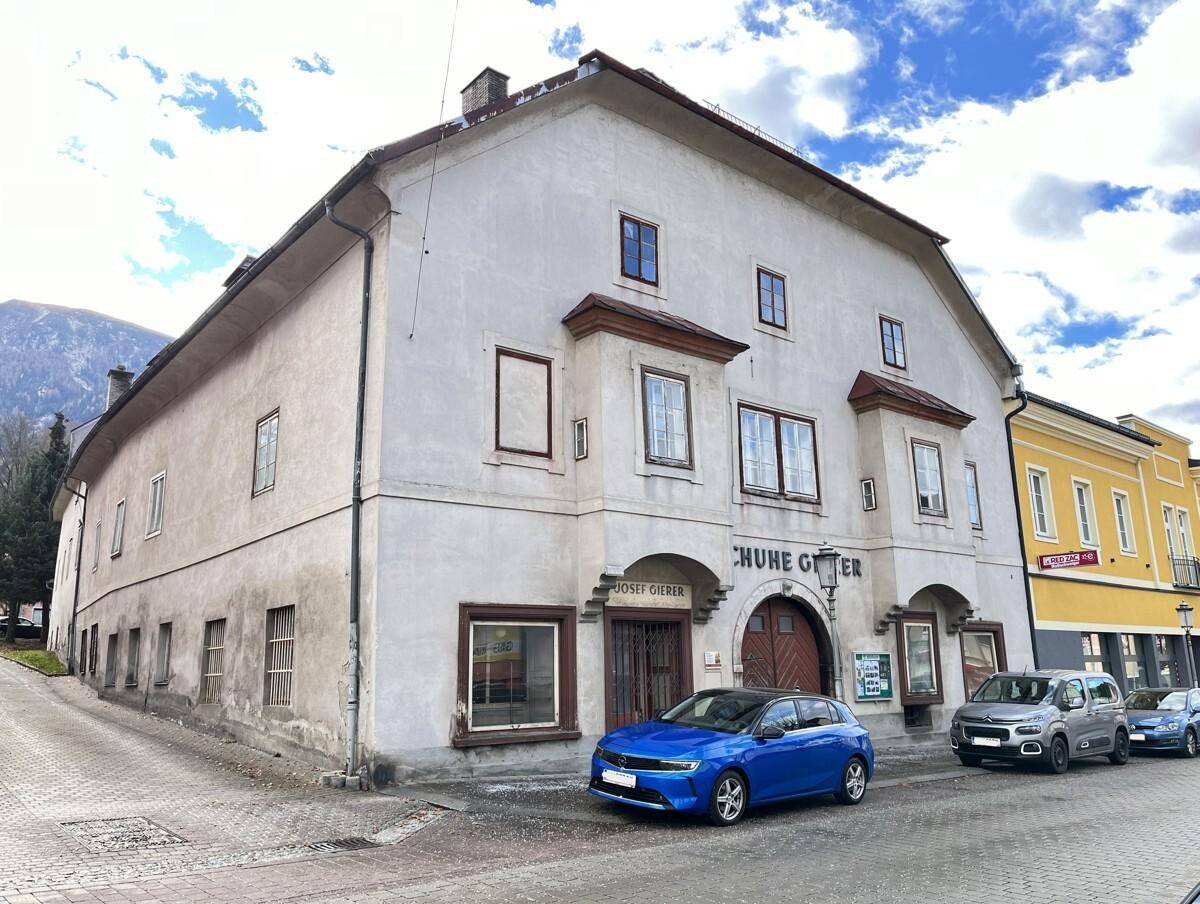 Historisches Gebäude an einer Straße mit mehreren Fenstern und einem Geschäftseingang im Erdgeschoss.