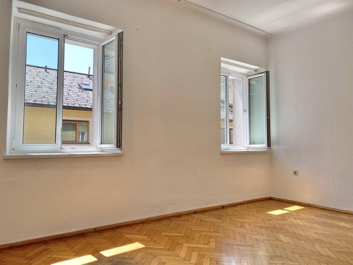 Heller Raum mit zwei Fenstern und Fischgrätparkett, ideal für individuelle Gestaltung und Nutzung.
