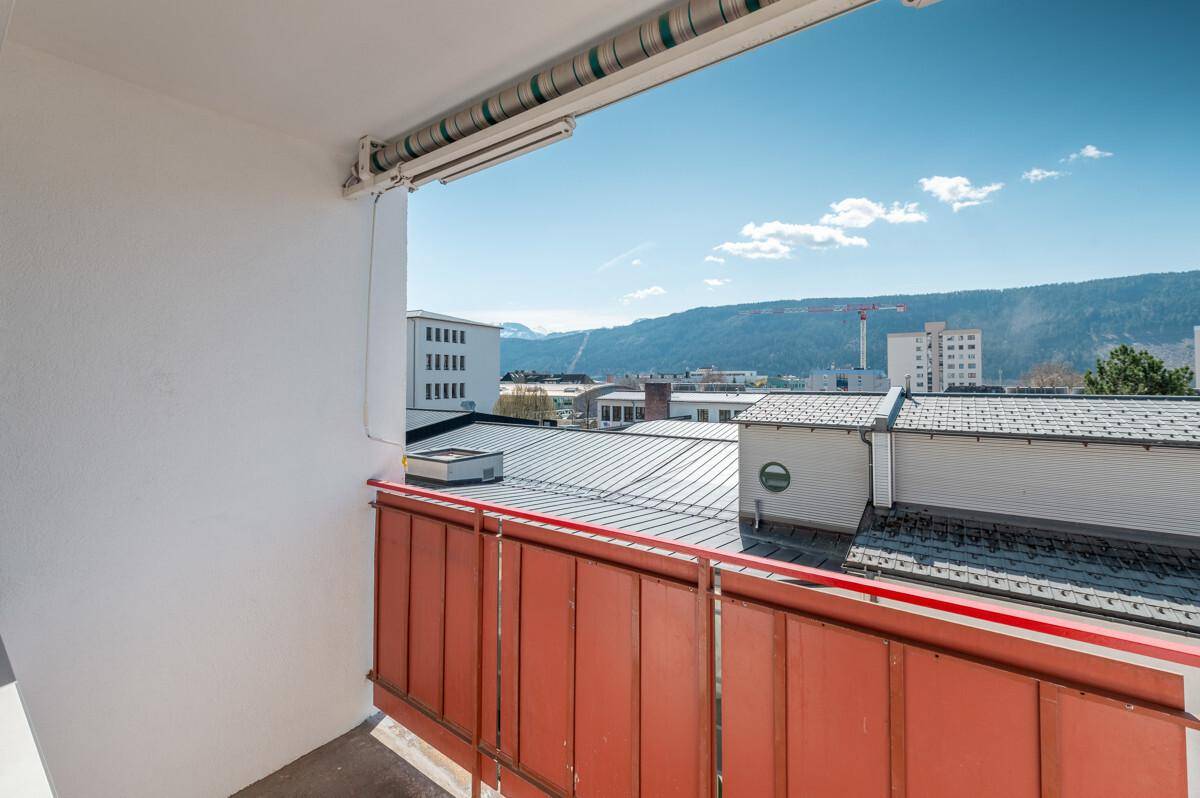 Sonniger Balkon mit Panoramablick auf die Stadt und die majestätische Bergkulisse.