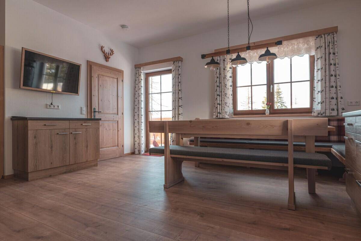 Geräumige Wohnküche mit Holzeinbauten, Essbereich und Zugang zum Balkon oder Garten.