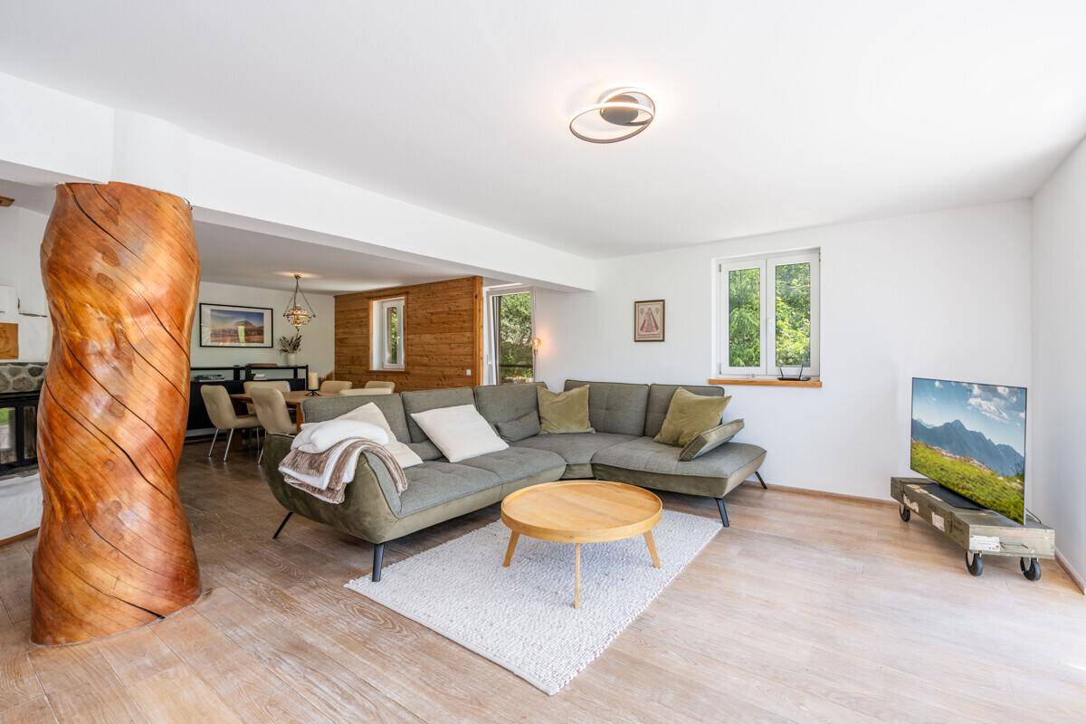 Geräumiger Wohn-Essbereich mit großem Sofa, Holzsäule und Blick auf den Essbereich.