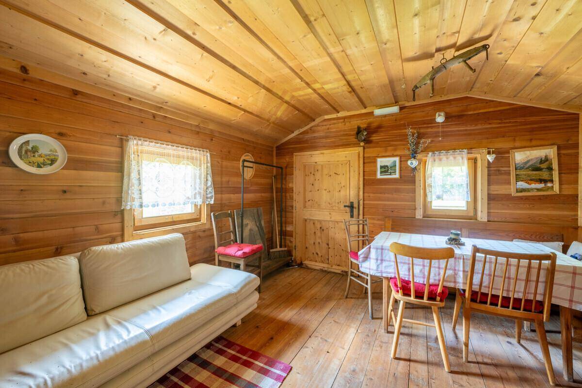 Gemütlicher Wohn-Essbereich in einer Holzhütte mit Sofa, Esstisch und Holzvertäfelung.