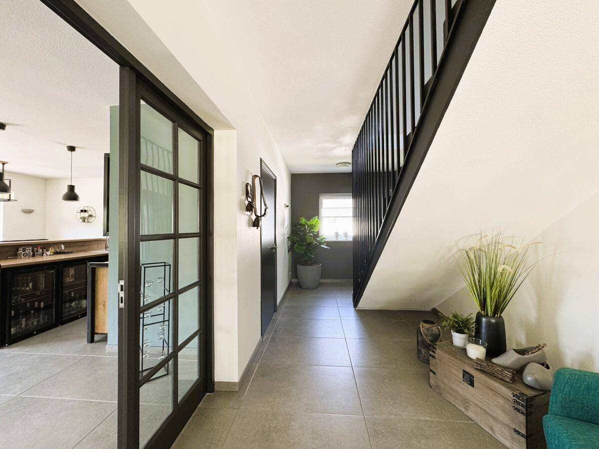 Geräumiger Flur mit Treppe, Glas-Schiebetür und modernem Design.