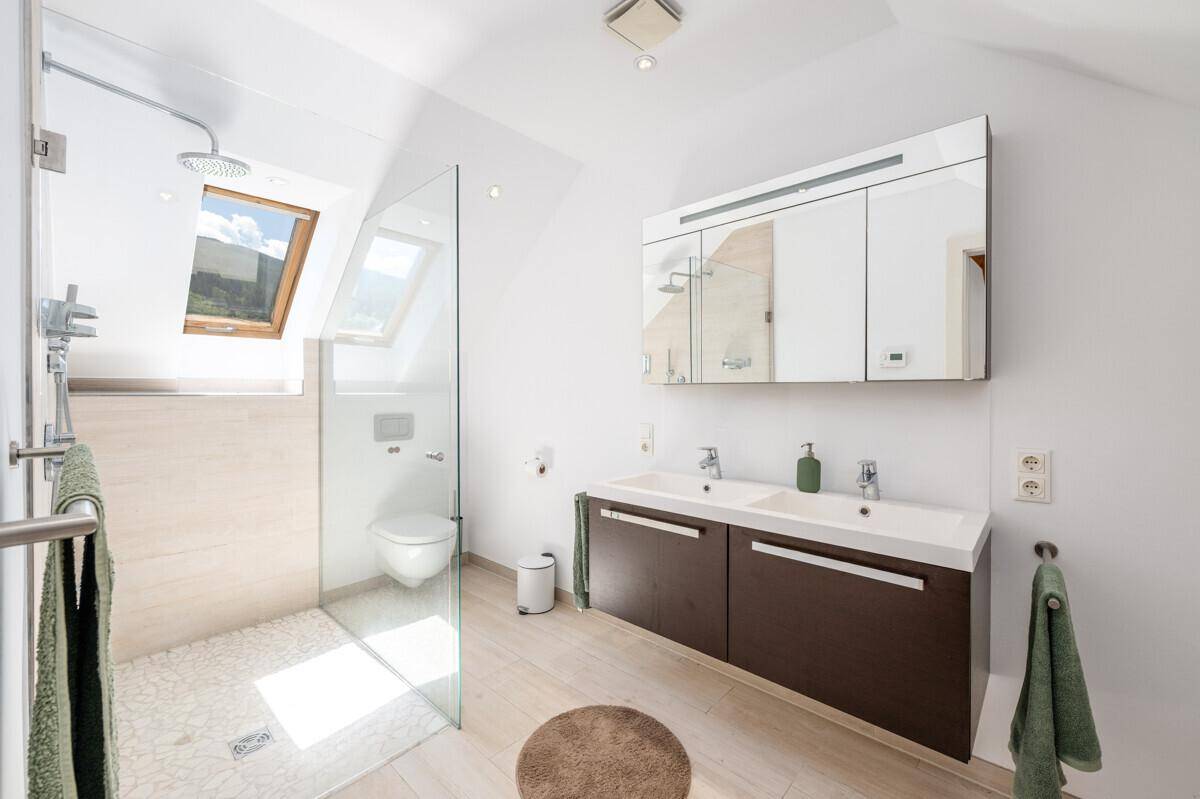 Modernes Badezimmer im Dachgeschoss mit begehbarer Dusche, Doppelwaschbecken und Dachfenstern.