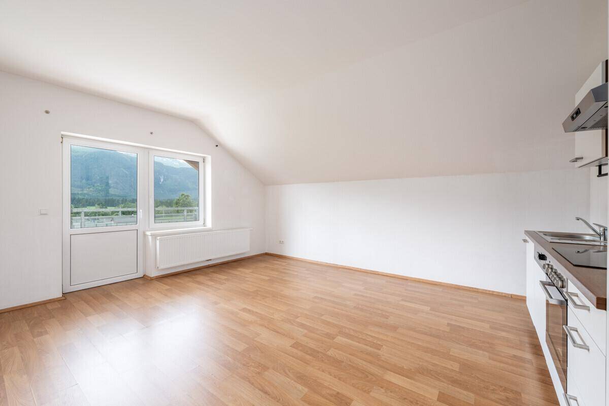 Offener Wohnbereich mit Küchenzeile, Laminatboden und Fenster mit Bergblick.