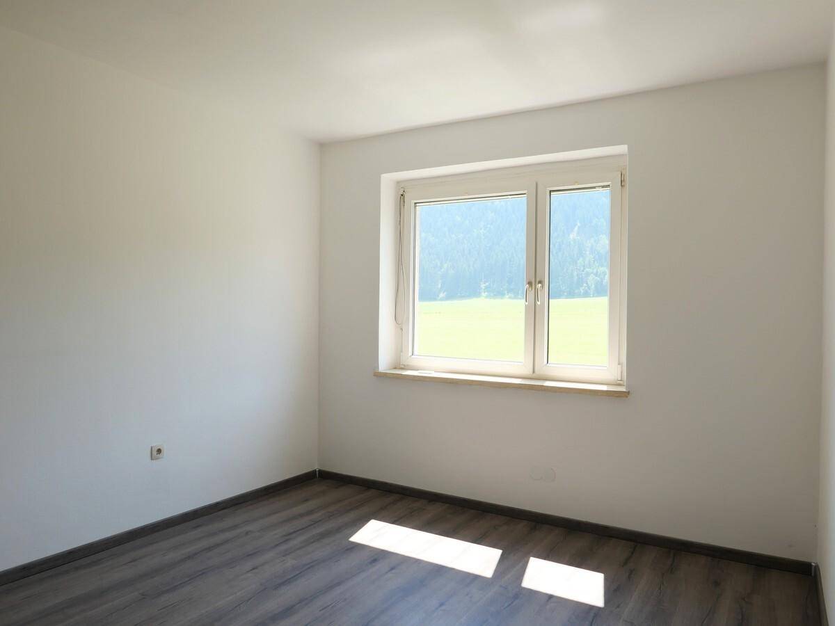 Helles Zimmer mit Laminatboden, großen Fenstern und weitem Blick ins Grüne.