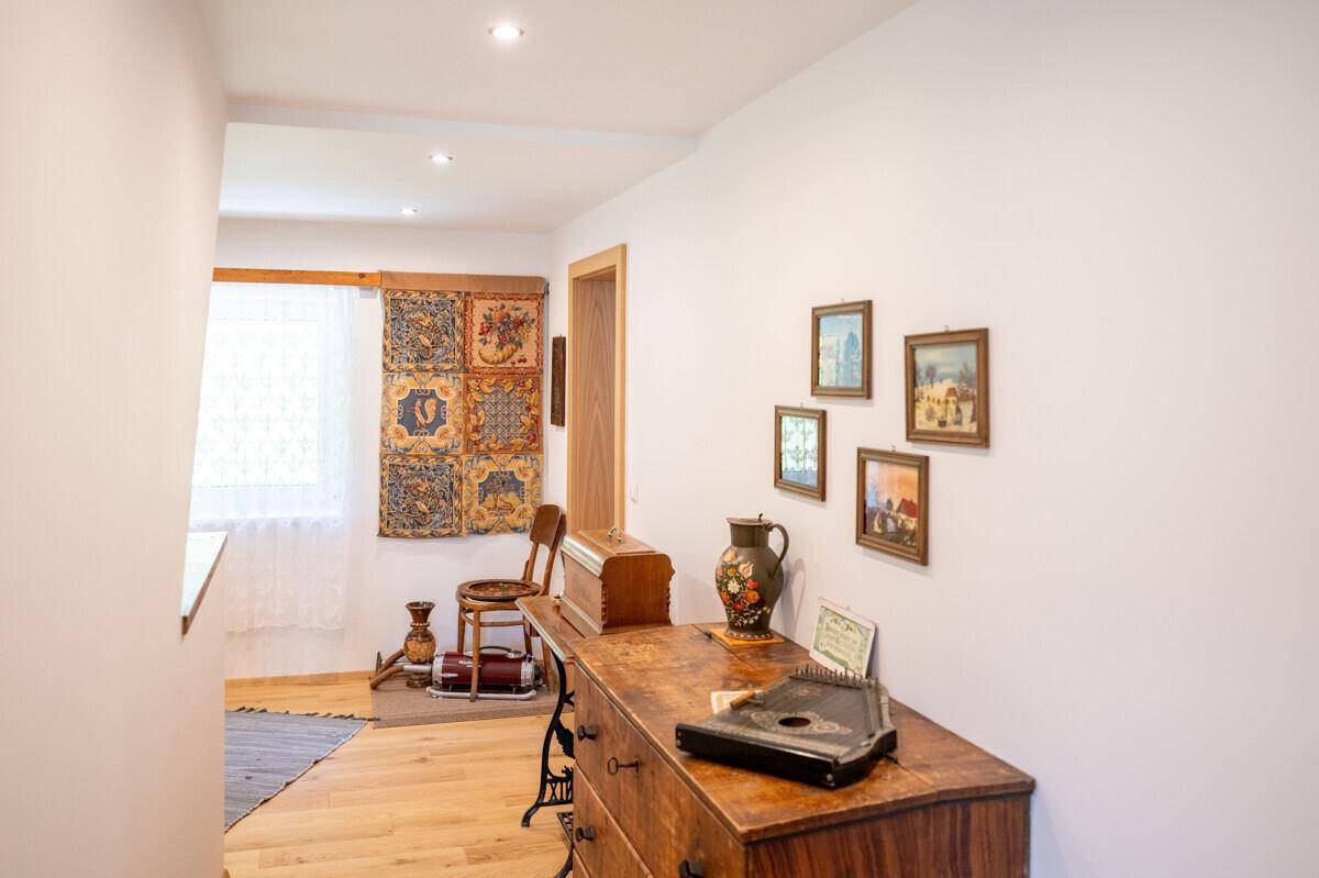 Heller Flur mit Holzboden, traditionellen Möbeln und einem Fenster mit Blick ins Grüne.