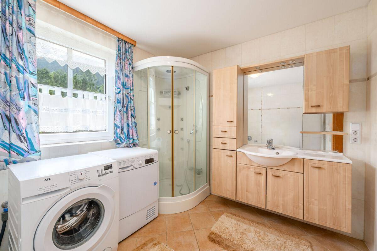 Badezimmer mit Duschkabine, Waschbecken, Waschmaschine und Trockner.