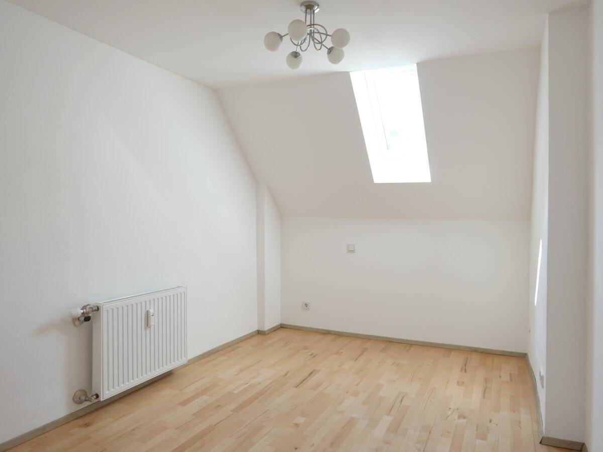 Lichtdurchfluteter Raum mit Dachschräge, Oberlicht und Parkettboden, ideal für Schlaf- oder Wohnbereich.