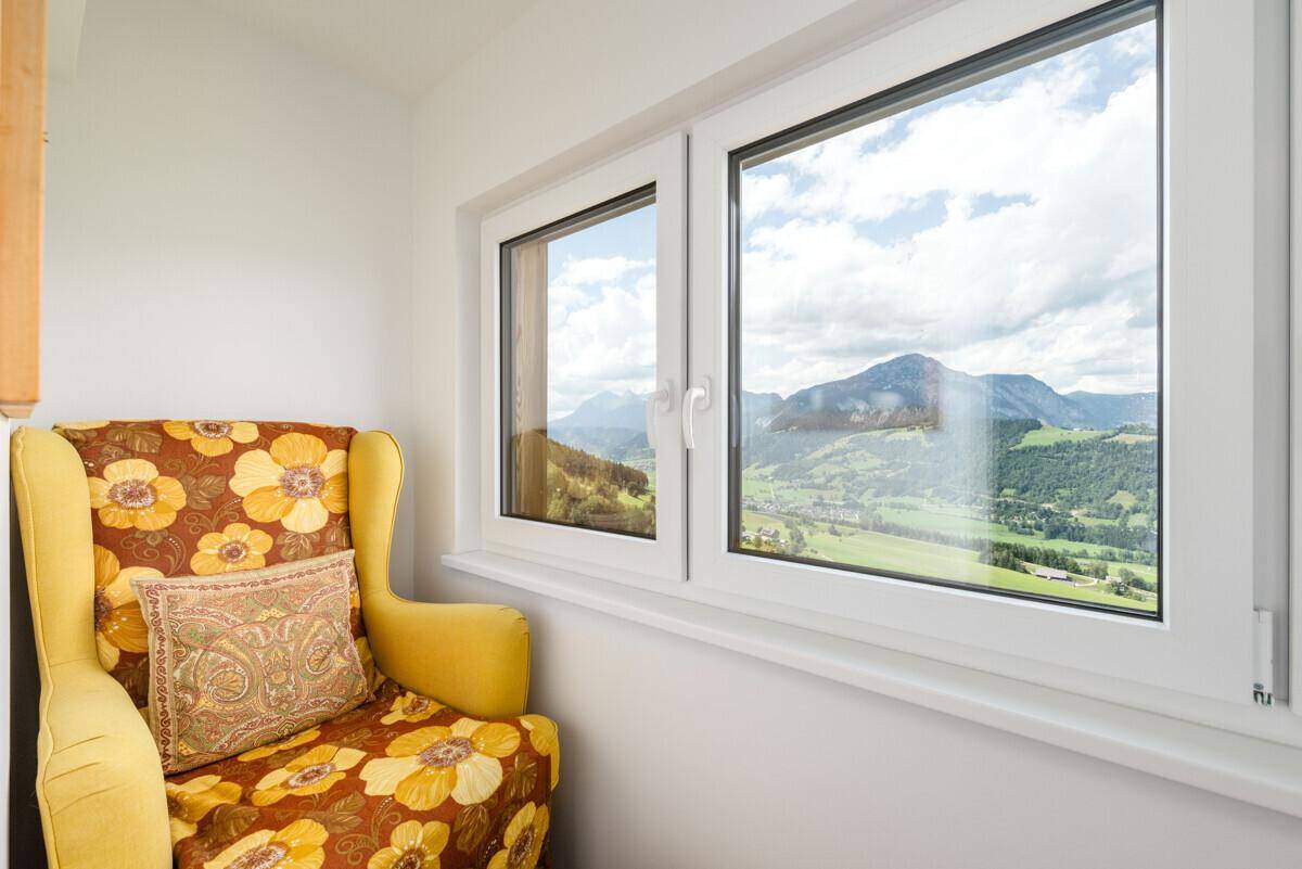 Gemütlicher Sessel am Fenster mit weitem Blick auf die umliegende Berglandschaft.