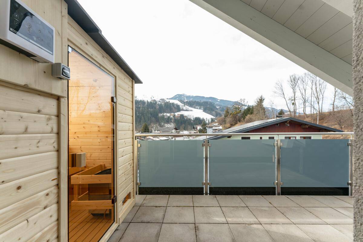 Außenterrasse mit Sauna und Panoramablick auf die verschneiten Berge.