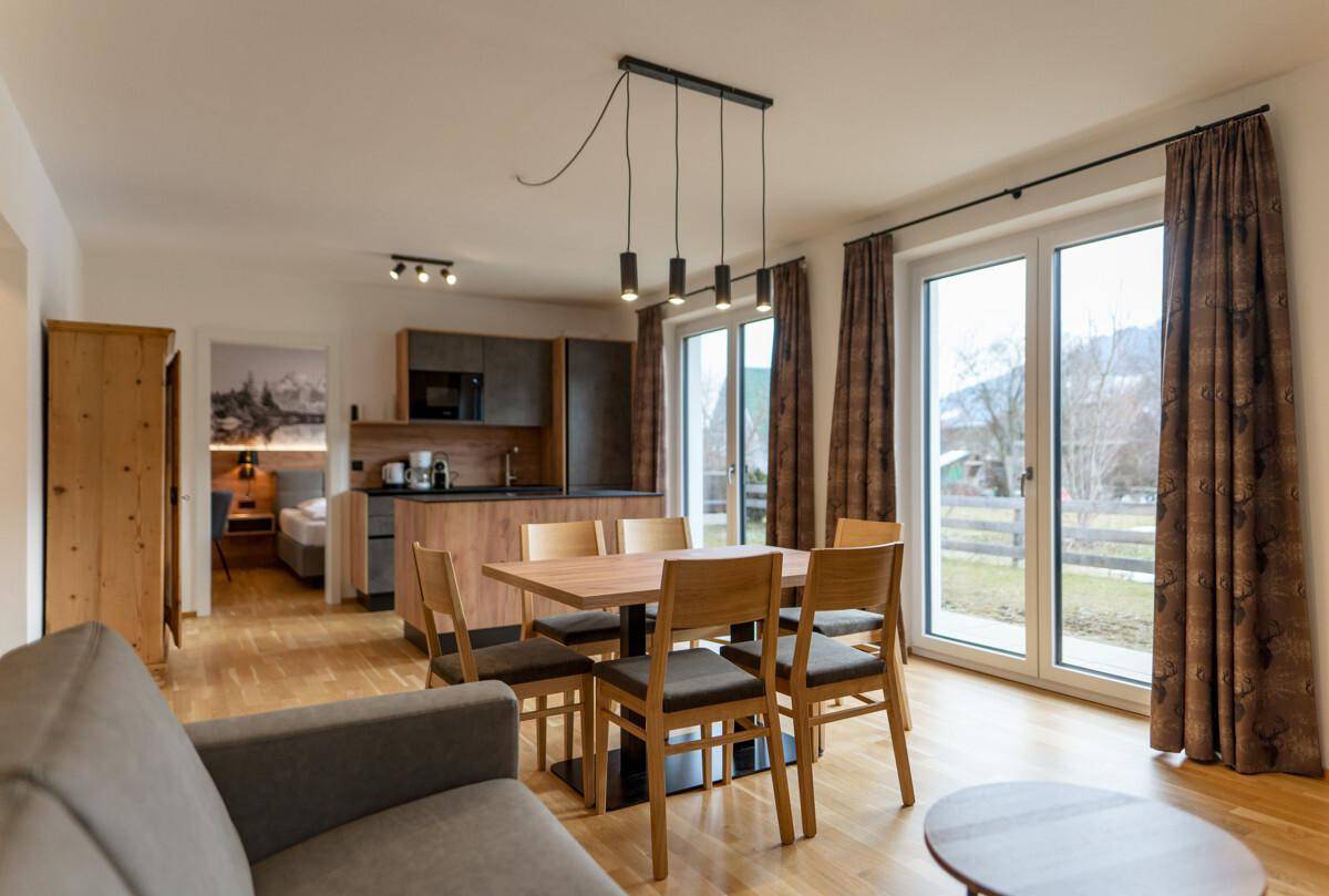Offener Wohn-Essbereich mit Holzboden, moderner Küche und Zugang zur Terrasse.