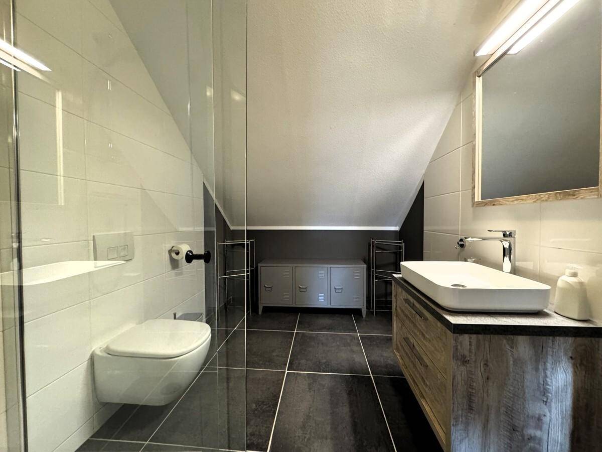 Modernes Badezimmer mit begehbarer Dusche, Waschtisch und Dachschräge.