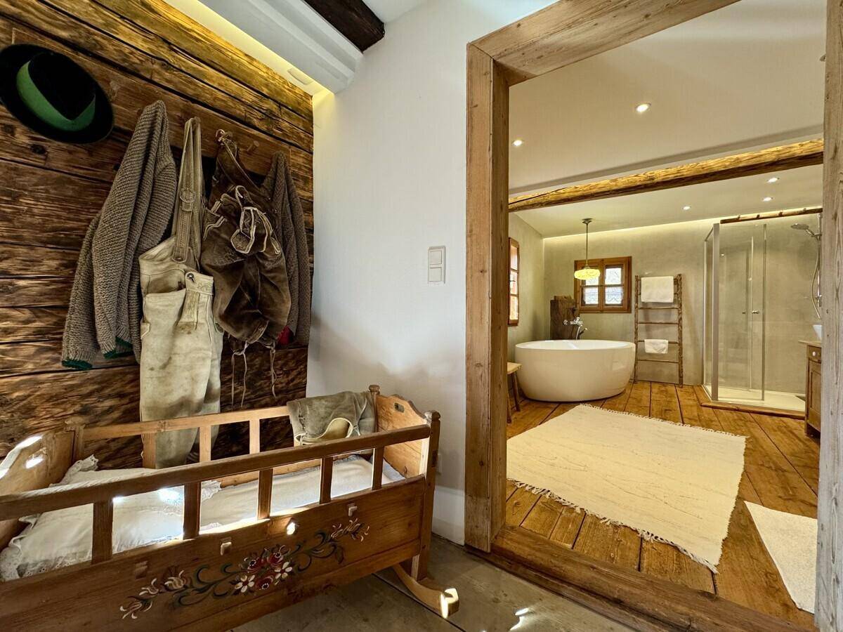 Blick vom Schlafzimmer in ein modernes Badezimmer mit freistehender Badewanne und Holzelementen.