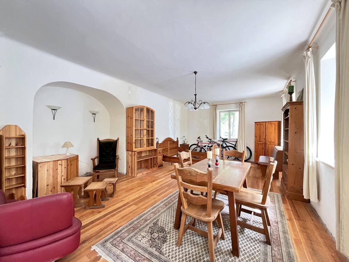 Geräumiger Wohn- und Essbereich mit Holzboden, traditionellen Holzmöbeln und Teppich.