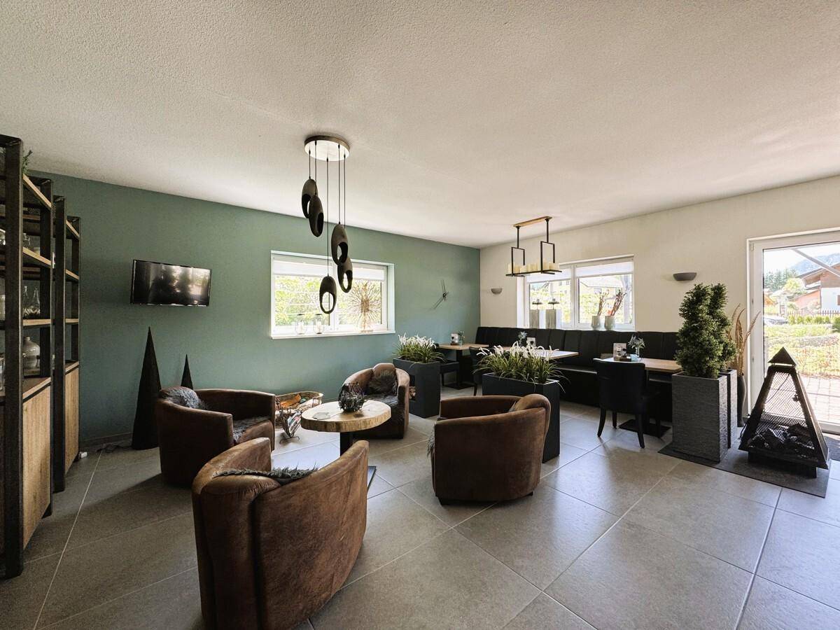 Geräumiges Wohnzimmer mit Sitzgelegenheiten, Regalen und Zugang zum Außenbereich.