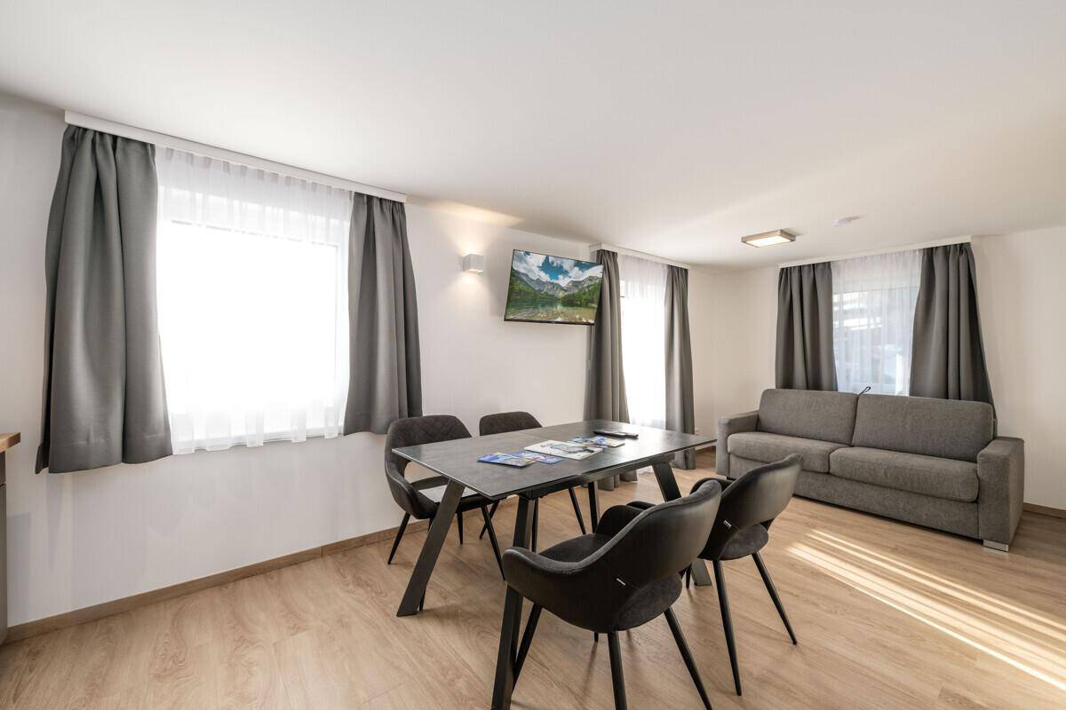 Geräumiger Wohn-Essbereich mit Esstisch, Sofa und Wandfernseher, hell und modern.