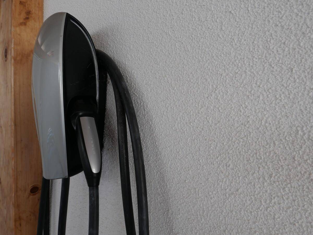 Nahaufnahme einer modernen Ladestation für Elektrofahrzeuge an einer strukturierten Wand.