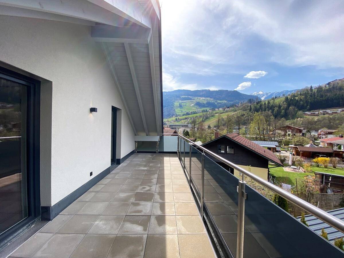 Langer Balkon mit Fliesenboden und weitem Blick auf die Bergwelt und das Tal.