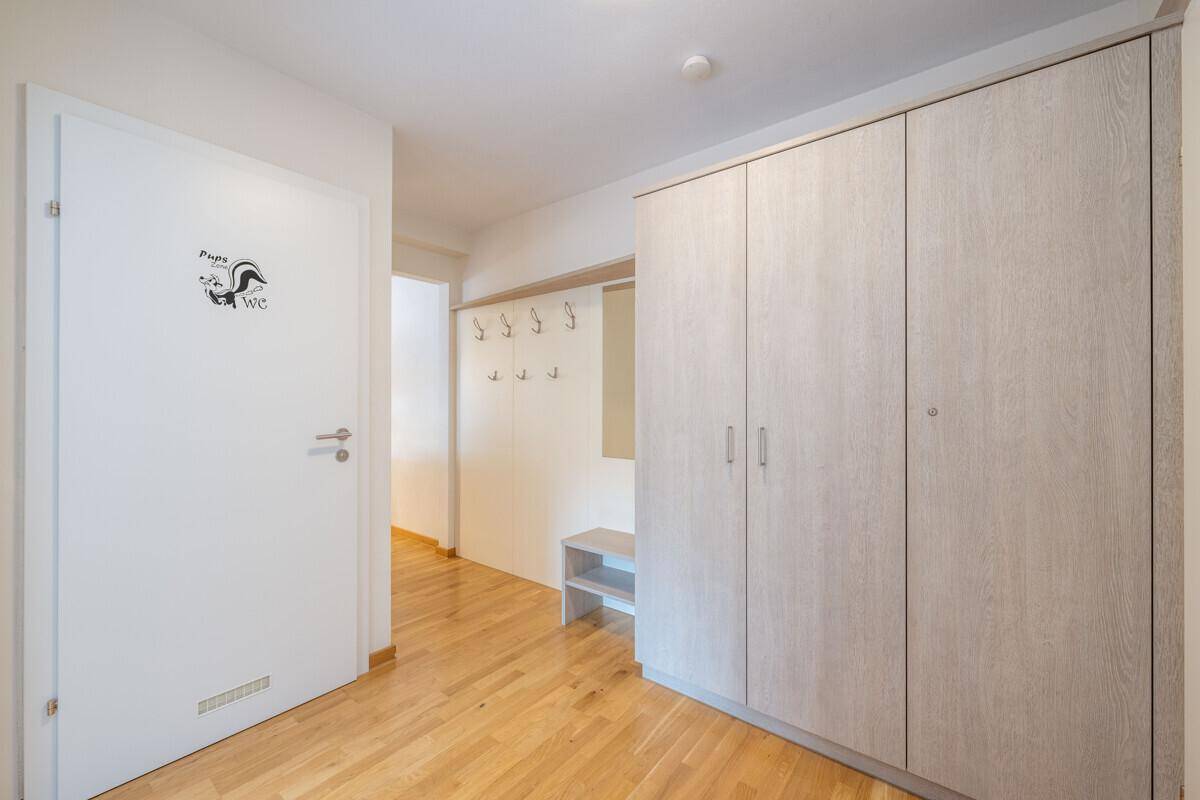 Flur mit Einbauschränken und Zugang zur Gästetoilette, ausgestattet mit Holzparkett.