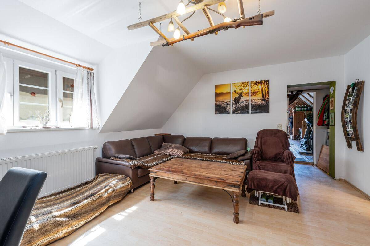 Gemütliches Wohnzimmer mit braunem Ledersofa, Holztisch und Fenster unter der Dachschräge.