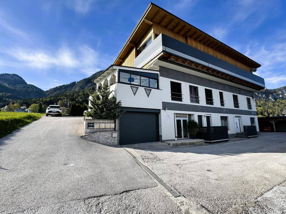 Mehrfamilienhaus mit moderner Architektur, Garage und weitem Blick auf die Berge.