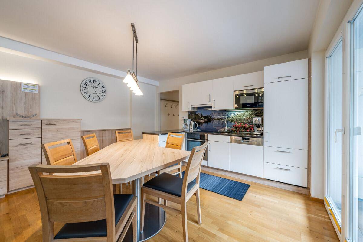 Helle Einbauküche mit Essbereich, modernen weißen Schränken und Zugang zum Balkon.