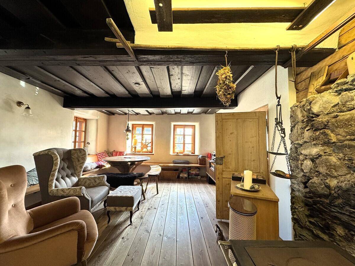 Gemütliches Wohnzimmer mit Holzdielenboden, bequemen Sesseln und einer markanten Steinwand, traditionell eingerichtet.