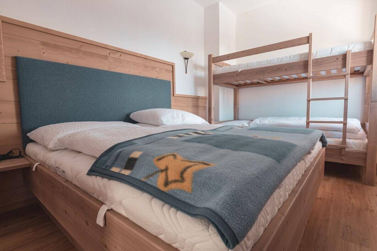 Schlafzimmer mit Doppelbett, Etagenbett und Holzmöbeln, ideal für Familien oder Gruppen.
