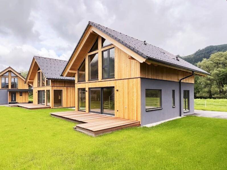 Moderne Häuser mit Holzterrassen, großen Fenstern und weitem Blick ins Grüne.